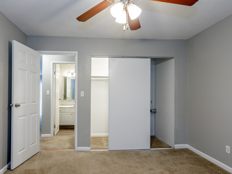 large carpeted room with ceiling fan and closet